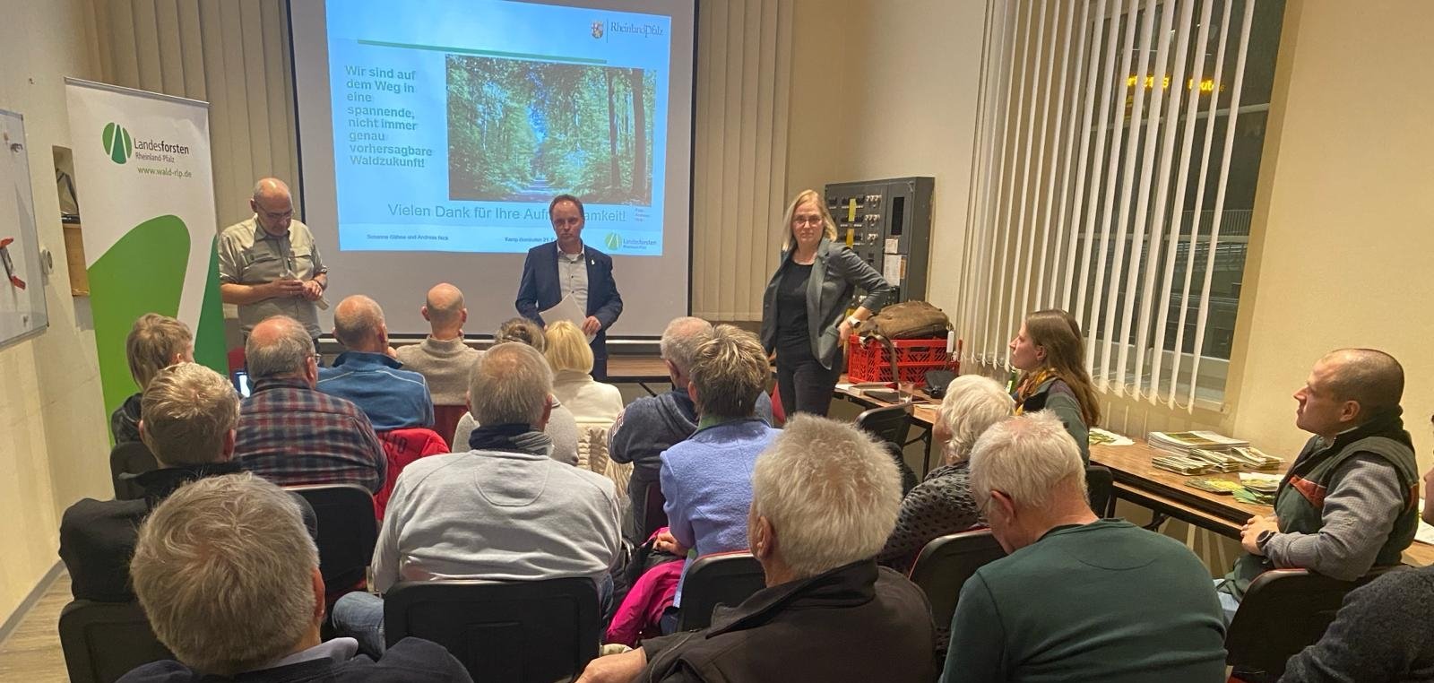 Circa 25 sitzende Menschen, die einem Vortrag zum Thema Waldentwicklung folgen. 