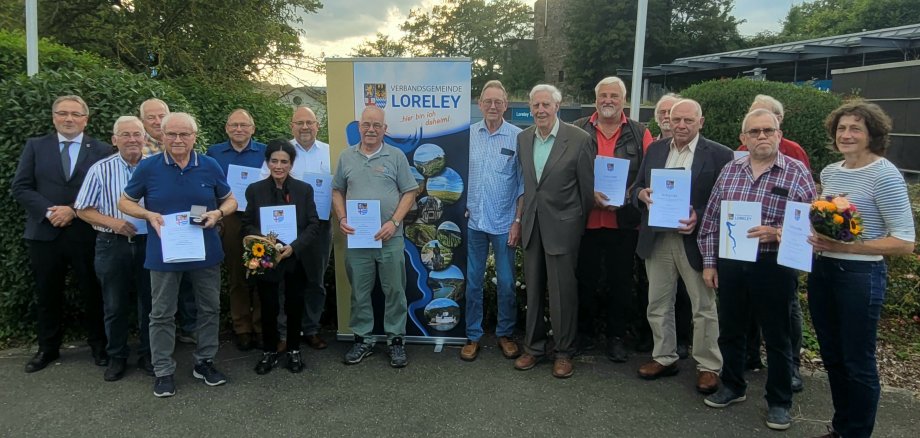 Ehrungen gesamt Die geehrten Rats- und Ausschussmitglieder sowie Stadt- und Ortsbürgermeister/innen posieren mit ihren Urkunden und Präsenten nebeneinander stehend für ein Foto.