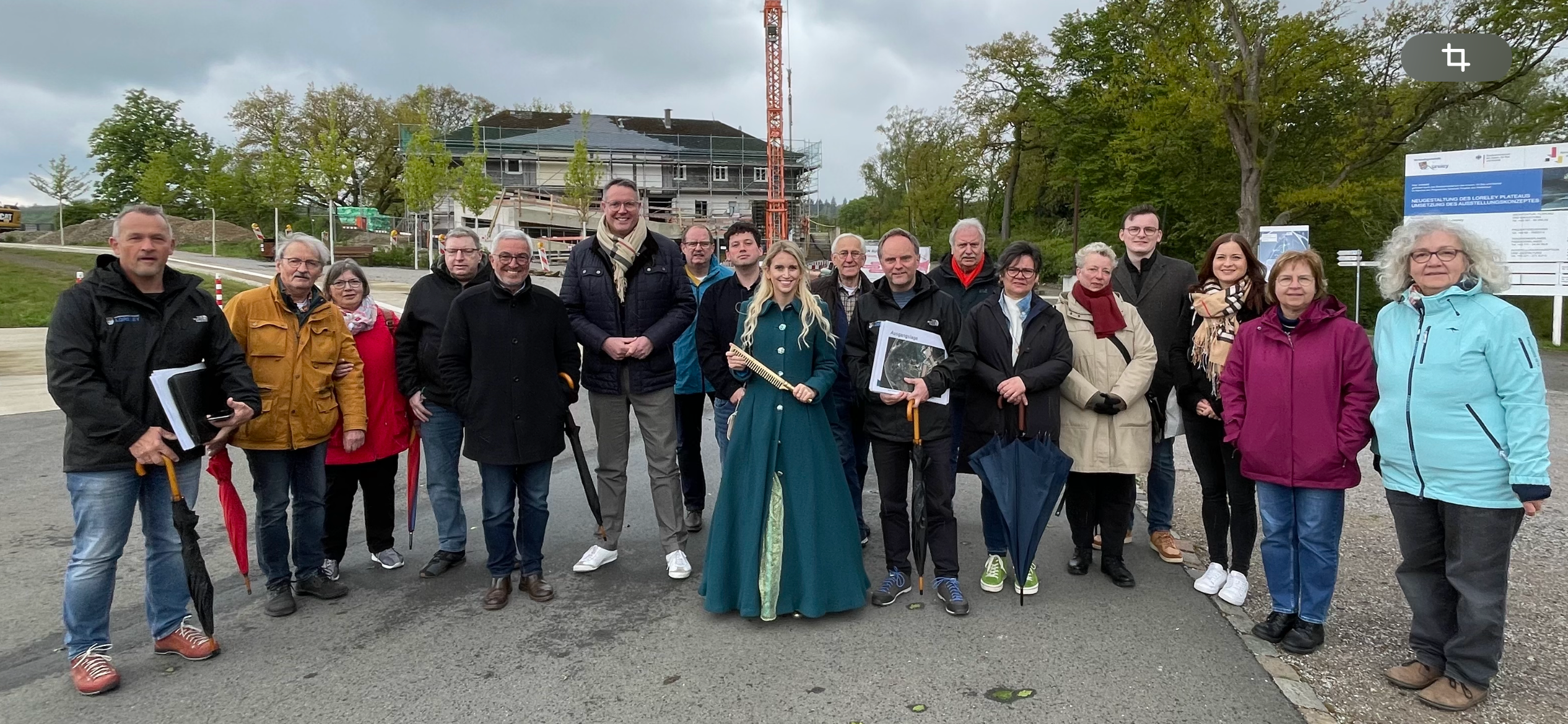 18 Personen stehen am Eingang zum Kultur- und Landschaftspark für ein Gruppenfoto zusammen. Das Wetter ist leicht bewölkt und im Hintergrund ist das ehemalige Turner- und Jugendheim mit einem Baukran zu sehen.