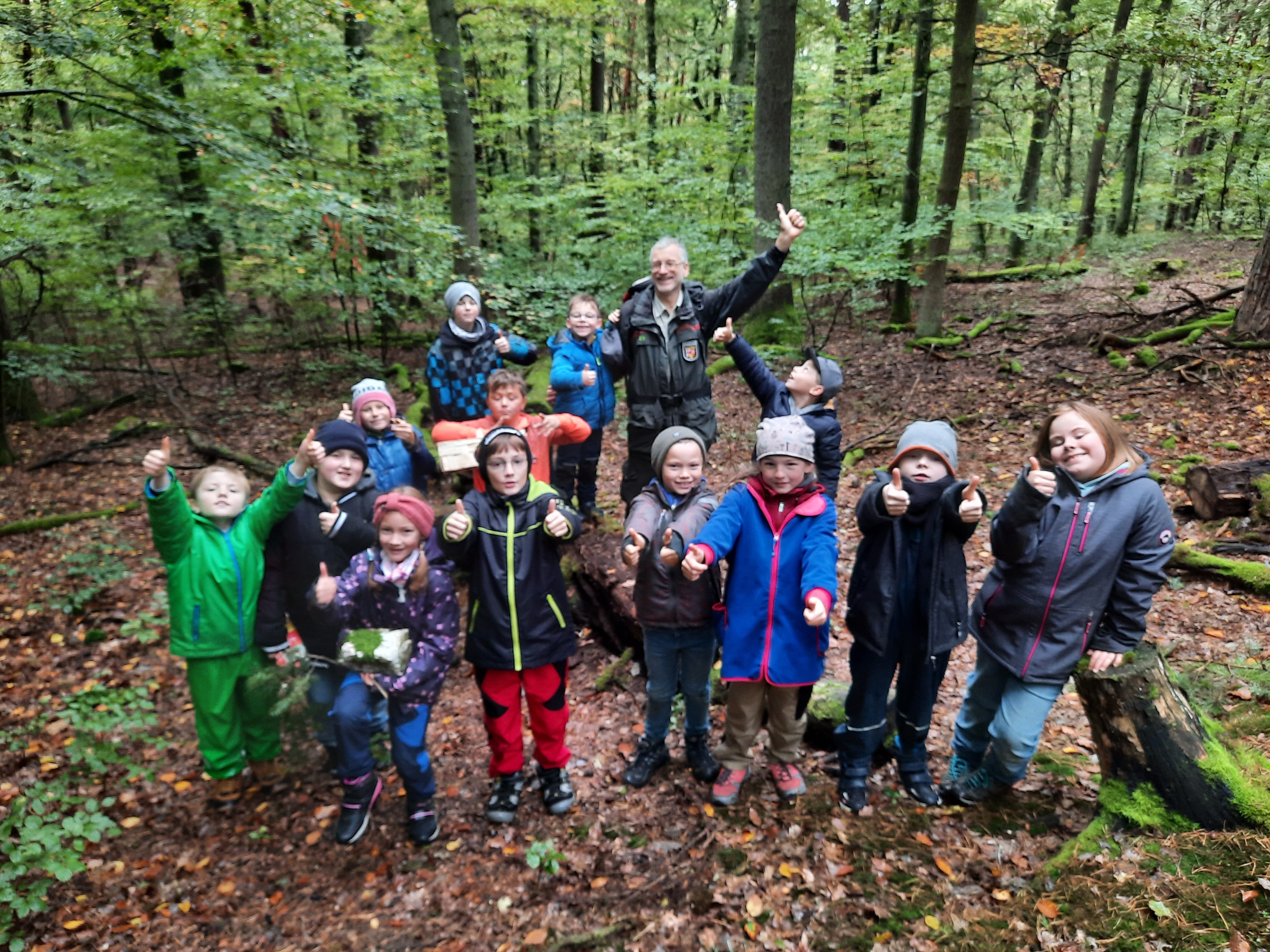 Ein Gruppenfoto der Kinder der Walderlebniswoche 2024 und Carsten Frenzel im Wald. 