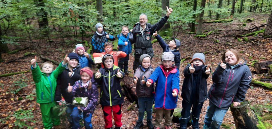 Ein Gruppenfoto der Kinder der Walderlebniswoche 2024 und Carsten Frenzel im Wald. 